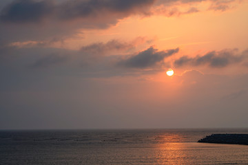 Naklejka na ściany i meble Seascape at Yellow glowing sun setting in the horizon with breakwater.
