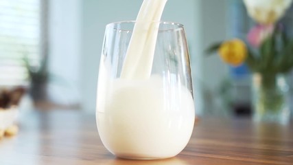 White cow milk being poured in to glass in slow motion. - Powered by Adobe