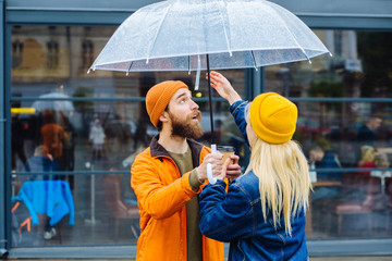 Side view portrait of lovely hipster couple face to face openinig transparent umbrella lsmiling...