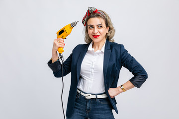 Model in white shirt, blue jacket, jeans with white belt, with yellow drill in hands, isolated on white background.