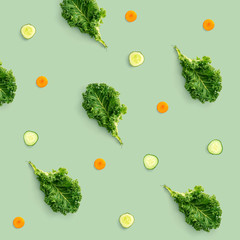 Creative pattern made of kale, cucumber and carrot on green background. Flat lay. Food concept.