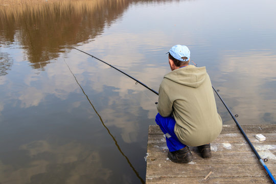 man sitting on a folding chair fishing in a lake