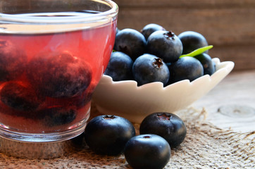 Blueberry tea in a glass cup and fresh blueberries on a burlap cloth on wooden background.Natural herbal summer beverage.Selective focus.