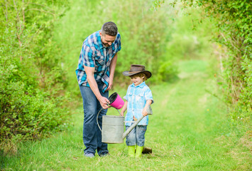 Naklejka na ściany i meble happy earth day. Family tree nursering. use watering can and pot. Garden equipment. Eco farm. small boy child help father in farming. father and son in cowboy hat on ranch. Joyful day