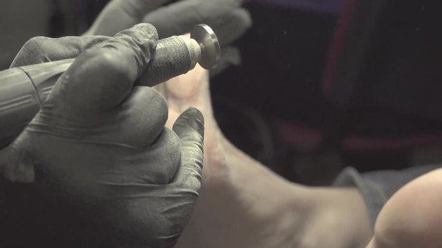 Removing fingernail cuticles with drill machine, polishing. Pedicure with a professional drill machine by using different drill bits. Peeling feet pedicure procedure.