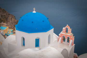 Tilt shift effect of blue dome and bell tower in the village of Oia