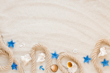 Different sea shells with nautical rope on sand