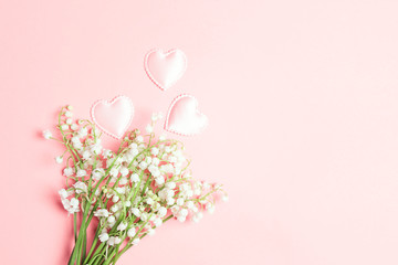 Lily of the valley flowers with love hears on a pink background.