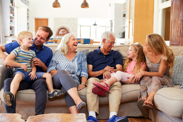 Multi-Generation Family Sitting On Sofa At Home Relaxing And Chatting