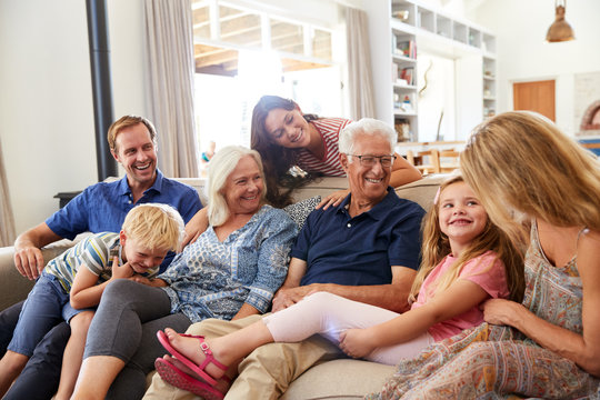 Multi-Generation Family Sitting On Sofa At Home Relaxing And Chatting