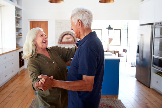 Senior Couple At Home Dancing In Kitchen Together