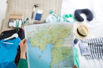 tourism, vacation and destination concept - close up of young woman with map preparing for travel at home