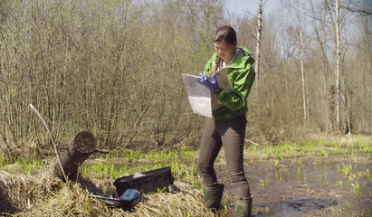 Environmentalist in the forest maps her location. Damage appreciation to nature. Scientific field work