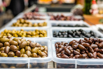 Assortment of olives on the marketplace. Rows of different types of olives in transparent plastic bowls.