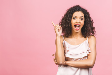 Portrait of happy dark skinned mixed race female model indicates with fore finger at blank copy space, shows place for your advertisement or promotional text. Lovely African American girl.