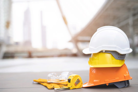 yellow and white hard safety wear helmet hat in the project at construction site building on concrete floor on city with sunlight. helmet for workman as engineer or worker. concept safety first.