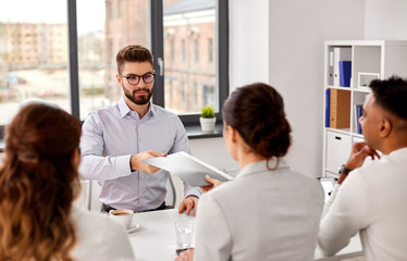 new job, hiring and employment concept - male employee giving folder and having interview with team...