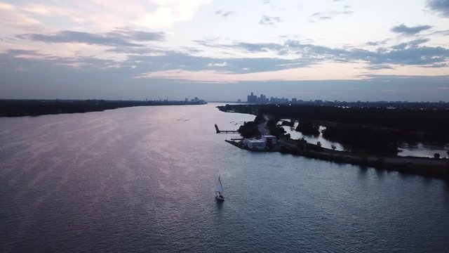 Belle Isle Detroit aerial view at sunset on a summer day. Bridge, buildings, boats visible in the distance. Island silhouette on the Detroit river with the Detroit skyline in the background.