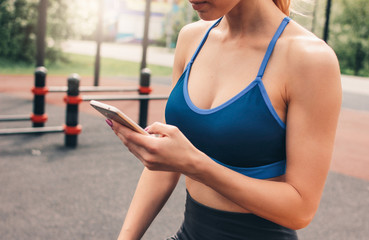 Crop photo of attractive fit young woman in sport wear doing training with mobile on the street workout area. The healthy lifestyle in city