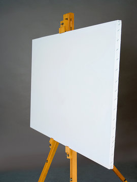 White empty artistic canvas on an easel for drawing images by an artist on a gray background in the studio