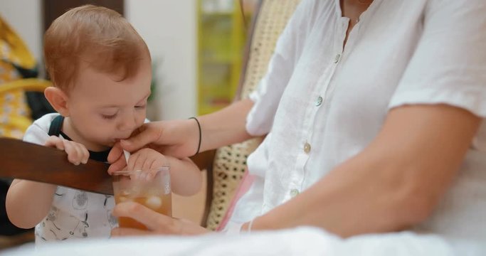 A little boy of 8 months old is trying an adult drink. The kid twists displeased face. real time. Shot on Canon 1DX mark2 4K camera