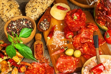 sausage or salami with chili pepper with herbs on wooden table. Spicy salami with chili. Unhealthy Fat Food.
