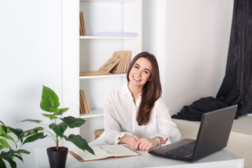 Positive young manager working on business project in office. business woman. Happy smiling young girl working in the office. Close-up portrait of an office worker. Attractive office worker standing. 