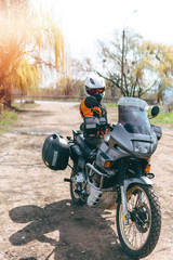 Obraz premium Biker girl wearing a motorcycle outfit, protective clothing, equipment, adventure touristic motorbike with side bags. outdoor travel, active traveler, vertical photo