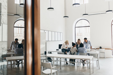 Indoor portrait of negotiation between international specialists sitting in conference hall. Foreign students preparing for tests together in university.