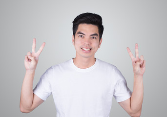 Portrait handsome young asian man wearing a white T-shirt  happy cheerful showing two fingers sign isolated on grey background. Asian man people. business success concept.
