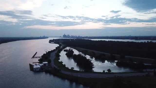 Belle Isle Detroit aerial view at sunset on a summer day. Bridge, buildings, boats visible in the distance. Island silhouette on the Detroit river with the Detroit skyline in the background.