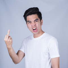 Portrait handsome young asian man wearing a white T-shirt fuck you sign  isolated on grey...