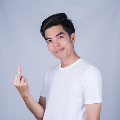 Portrait handsome young asian man wearing a white T-shirt fuck you sign  isolated on grey...