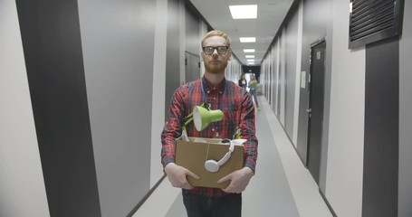 Cheerful male employee holding box with belongings