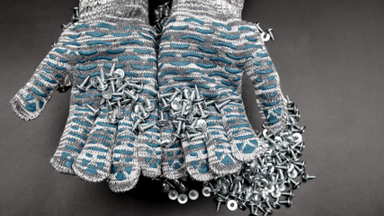 Sharp screws in building gloves on a black background