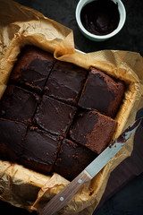Delicious fresh baked healthy vegan moist dark chocolate brownies dessert or sponge cake with coffee frosting cut in squares on baking paper top view.Vertical orientation.Selective focus