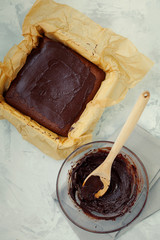 Preparation homemade square delicious healthy vegan moist dark chocolate brownies dessert or sponge cake with coffee frosting on grey textured background top view.Vertical orientation