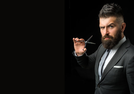 Confident barber at barbershop. Barber and hairdresser salon. Beard care, perfect beard. Bearded man in formal business suit. Brutal male hipster cut hair with hairdressing scissors - copy space