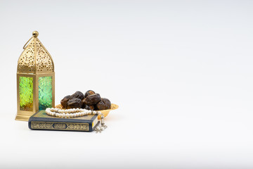 Lantern, Dates, Koran and Rosary on white background with selective focus and crop fragment. Ramadan, Religion and Copy space concept