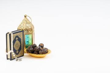 Lantern, Dates, Koran and Rosary on white background with selective focus and crop fragment. Ramadan, Religion and Copy space concept
