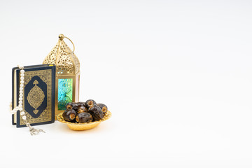 Lantern, Dates, Koran and Rosary on white background with selective focus and crop fragment. Ramadan, Religion and Copy space concept