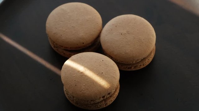 Beige macaroons on a dark plate