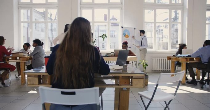 Camera moves right along modern light loft office, multiethnic business people working at healthy workplace atmosphere.