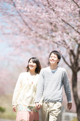 桜の前で手をつなぐカップル