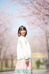 桜並木道で振り返る女性