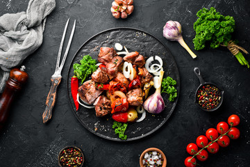 Kebab in a plate. Baked meat with onions and tomatoes. Barbecue. Top view. Free space for your text. Rustic style.