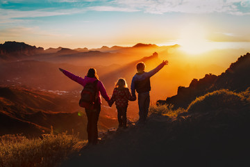 Happy mother with kids travel in sunset mountains