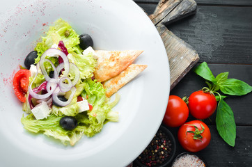 Greek salad. Vegetable salad with feta cheese, olives and cherry tomatoes. In the plate. Top view. Free space for your text. Rustic style.