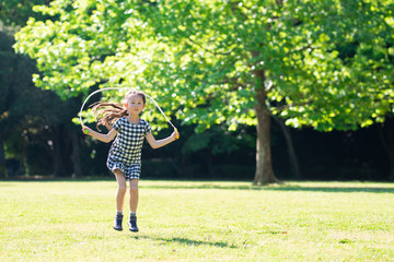 芝生で縄跳びをする女の子 - obrazy, fototapety, plakaty
