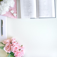 lifestyle flat lay with different accessories; flower bouquet, pink roses, open book, Bible, pen,...